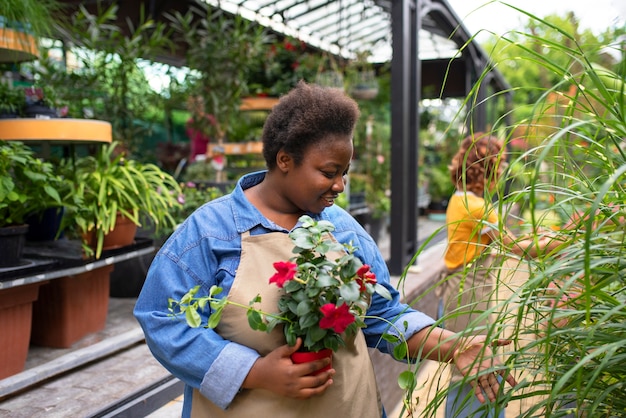 Gratis foto medium shot zwarte vrouw die een bloemenzaak runt