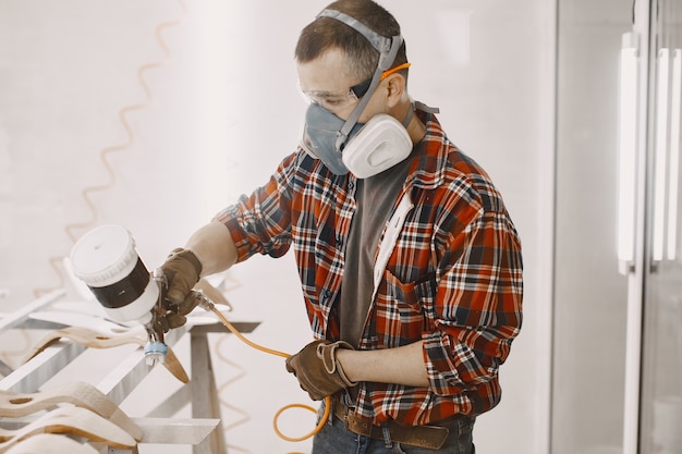 Meesterschilder in een fabriek die hout schildert met een spuitpistool