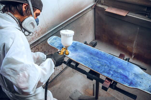 Meesterschilder in een fabriek - industrieel hout schilderen met spuitpistool.