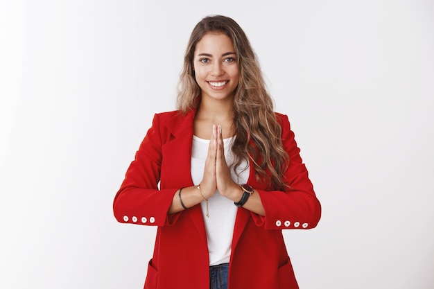 Meisje begroet je op een boeddhistische manier. Glimlachende aantrekkelijke charmante blanke vrouw met krullend haar die handpalmen bij elkaar houdt, bidt, glimlacht vriendelijk en toont namaste welkomstgebaar, uitnodigende aziatische gasten komen binnen