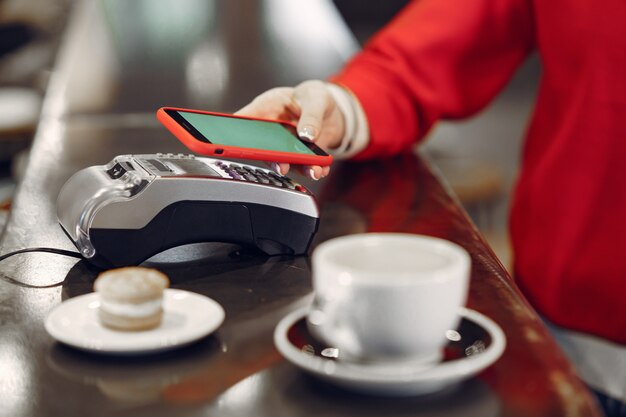 Meisje betaalt voor haar latte met een smartphone door contactloze PAY PASS-technologie