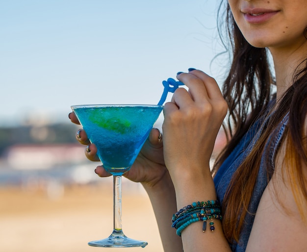 Gratis foto meisje dat de blauwe cocktail van de lagunealcohol met blauwe pijpen drinkt