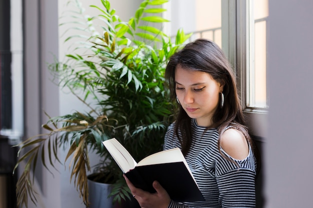 Gratis foto meisje dat een boek thuis leest