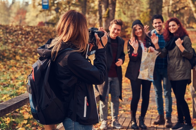 Meisje dat een foto maakt van haar vrienden. Groep jonge vrienden die door bos wandelen. Reizen, wandelen, avontuur concept.