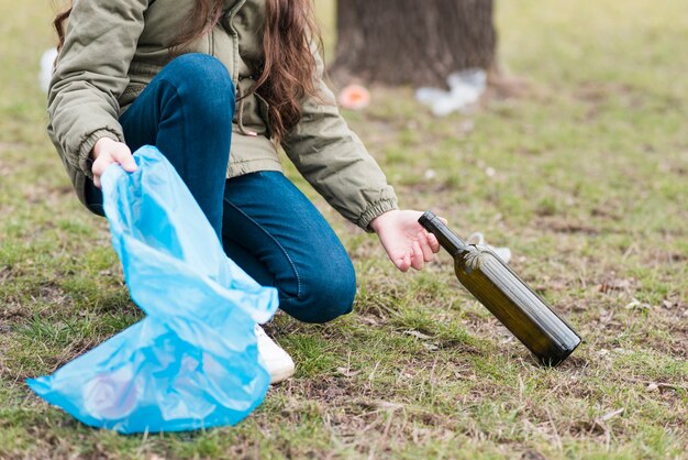 Meisje dat een glasfles schoonmaakt van grond