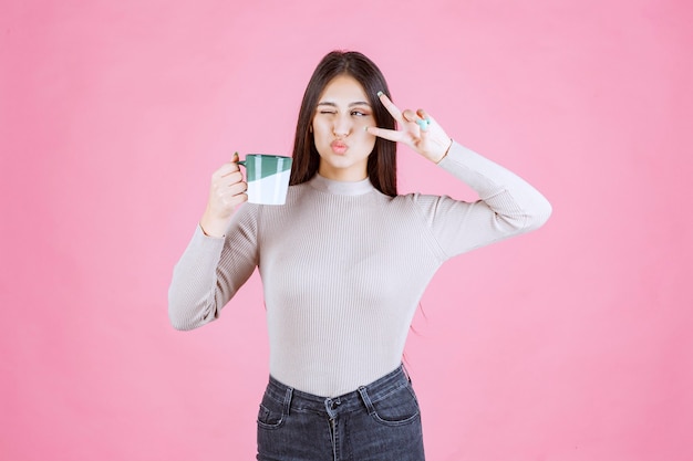 Meisje dat een koffiemok houdt en vredesbericht verzendt