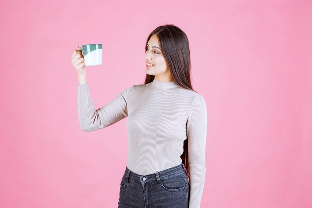 Meisje dat een koffiemok van de witgroene kleur houdt en zich positief voelt