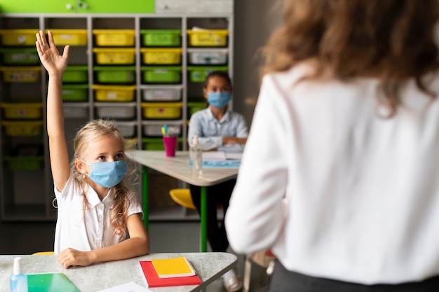 Gratis foto meisje dat een vraag in de klas wil beantwoorden