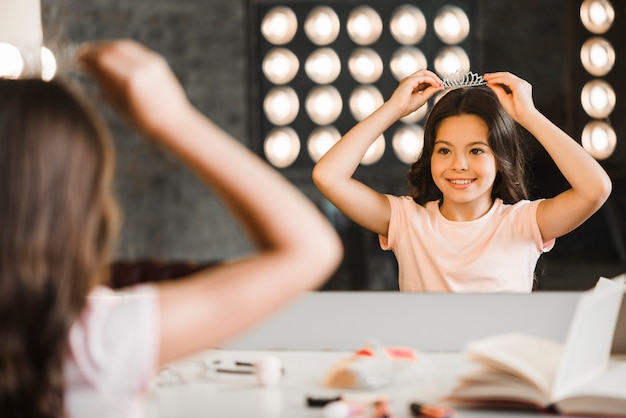 Meisje dat haar gedachtengang in spiegel bij make-upruimte bekijkt