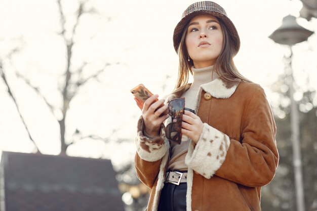 Meisje dat in een de lentestad loopt en een telefoon met behulp van