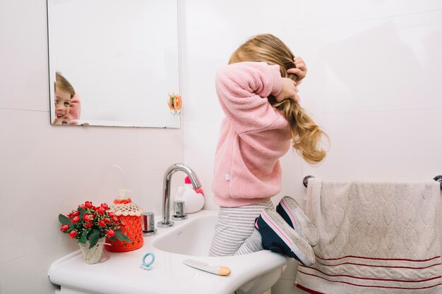 Meisje dat in spiegel kijkt die haar haar bindt