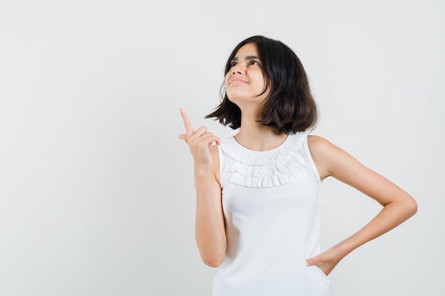 Meisje dat in witte blouse benadrukt en vrolijk kijkt. vooraanzicht.