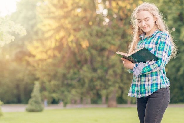 Meisje dat met boek in park bestudeert