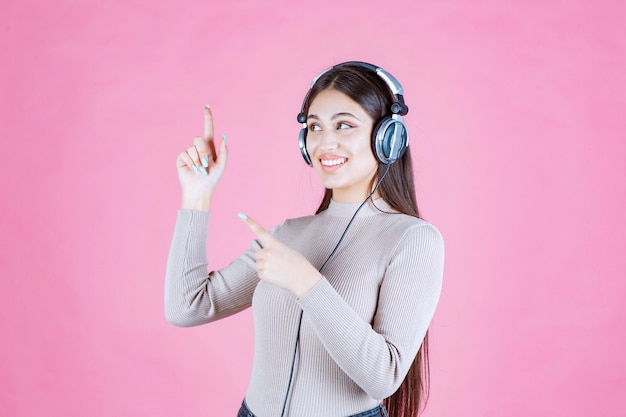 Meisje dat met hoofdtelefoons de muziek luistert en benadrukt