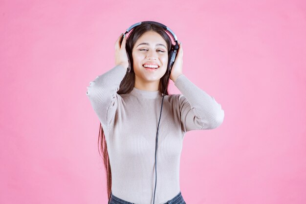 Meisje dat met hoofdtelefoons de muziek luistert en zich gelukkig voelt