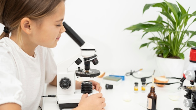 Meisje dat microscoop onderzoekt