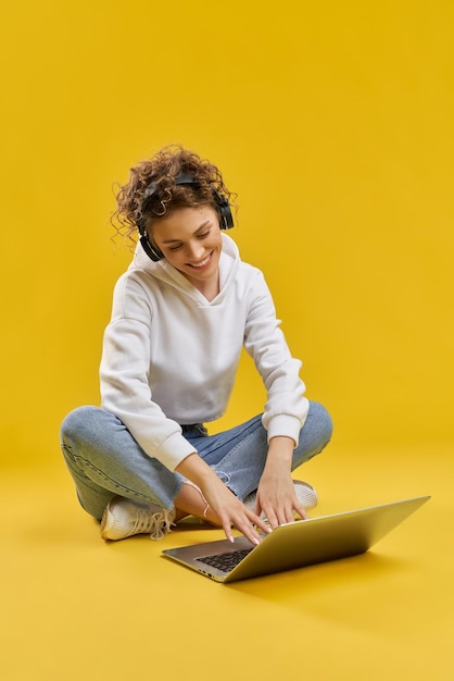 Meisje dat op benen zit en naar laptop kijkt