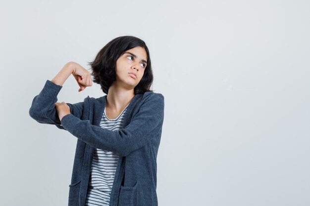 Meisje dat spieren van de arm in t-shirt toont