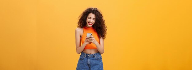 Meisje dat tijd doorbrengt op internet en sms't met vriendberichten via een smartphone die lacht terwijl ze naar devi kijkt