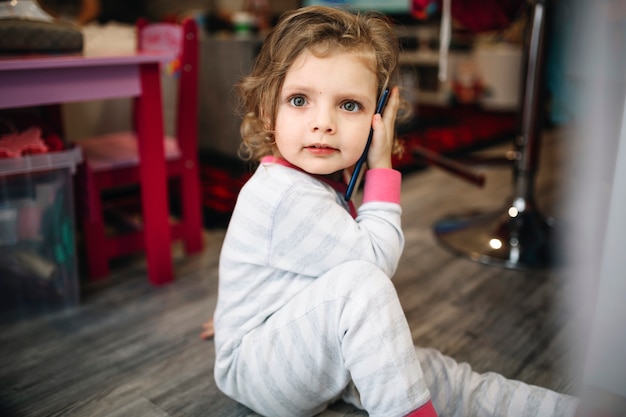 Meisje die op smartphone spreken en camera bekijken