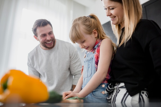 Meisje die ouders helpen om groenten te snijden