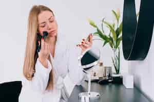 Gratis foto meisje doet haar make-up in de badkamer