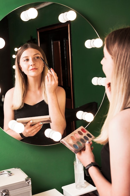 Meisje doet haar make-up in een groene kamer