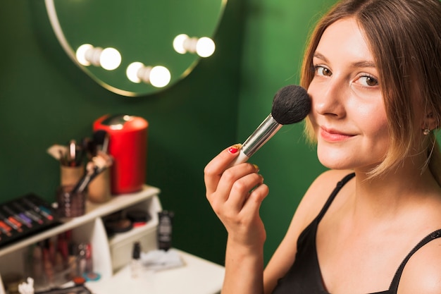 Gratis foto meisje doet haar make-up in een groene kamer