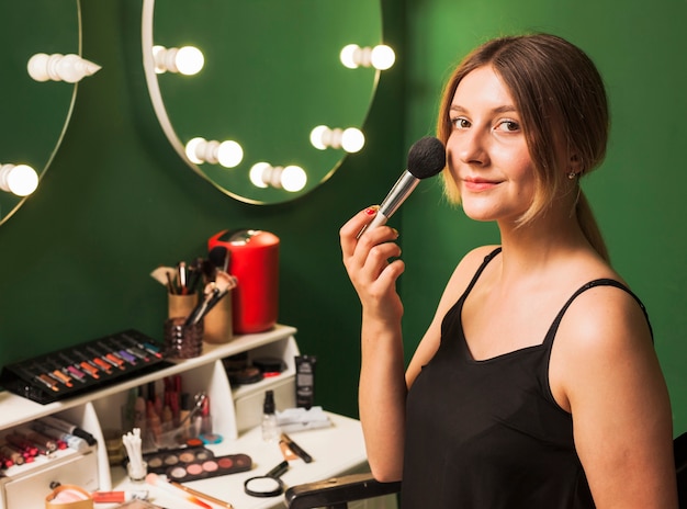 Meisje doet haar make-up in een groene kamer