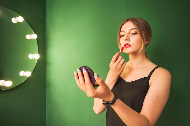 Meisje doet haar make-up in een groene kamer