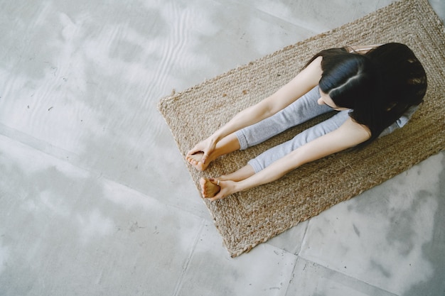 Meisje doet yoga oefeningen thuis in de buurt van sofa en raam in sportkleding