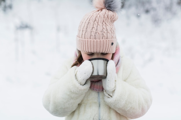 Gratis foto meisje drinken uit thermoskan cap