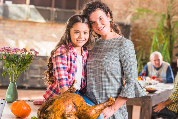 Meisje en vrouw die dichtbij gebakken kip koesteren