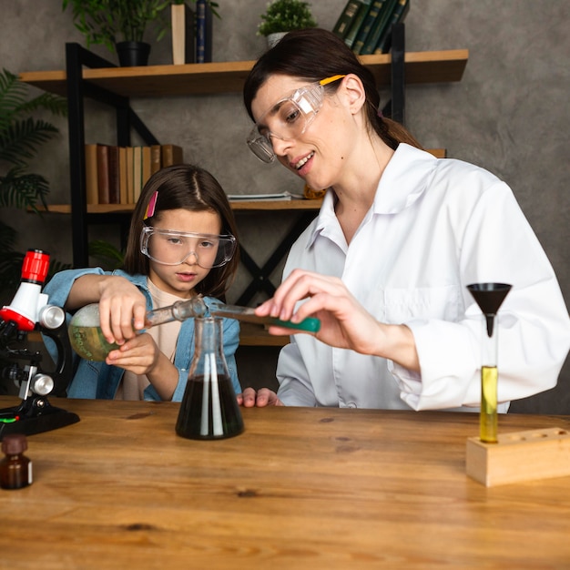 Meisje en vrouwelijke leraar doen wetenschappelijke experimenten met Microscoop