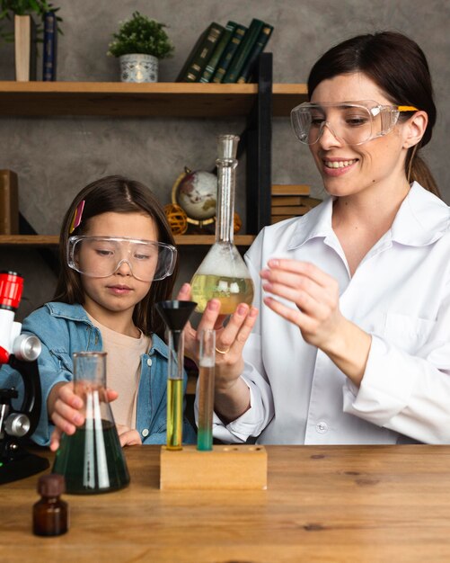 Meisje en vrouwelijke leraar doen wetenschappelijke experimenten met reageerbuizen