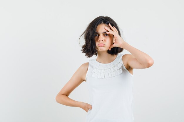 Meisje hand aan hoofd houden in witte blouse en depressief, vooraanzicht kijken.