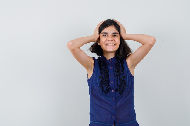 Meisje hand in hand op het hoofd in blauwe blouse en op zoek gelukkig. vooraanzicht.