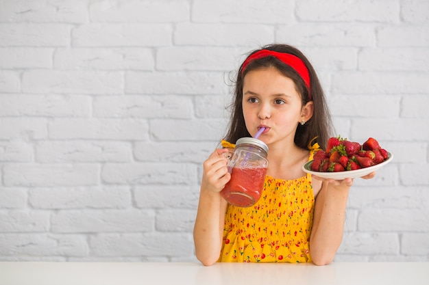 Meisje het drinken de plaat van de sapholding van aardbeien