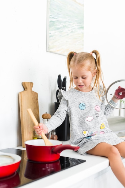 Gratis foto meisje het koken in keukenzitting op keuken worktop