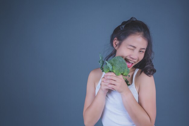 Meisje houdt de groenten op een grijze achtergrond.