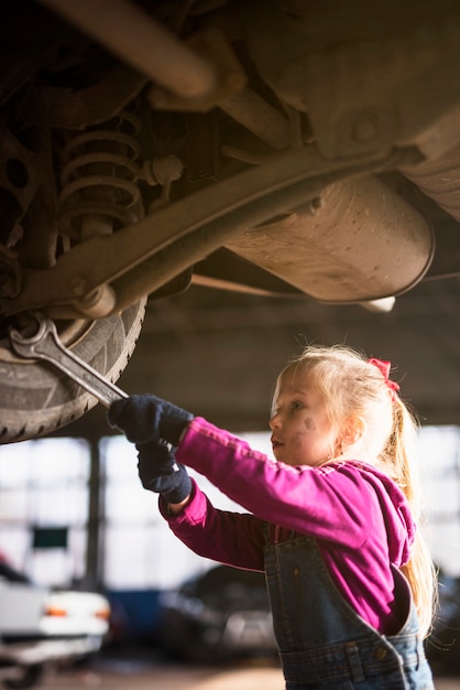 Meisje in algemene het herstellen van auto met moersleutel