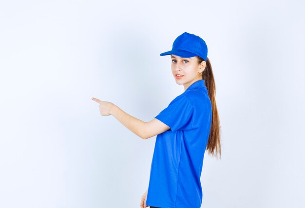 Meisje in blauw uniform dat naar de linkerkant wijst.