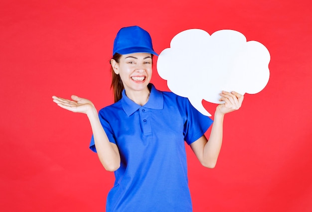 Meisje in blauw uniform en baret met een denkbord in de vorm van een wolk.