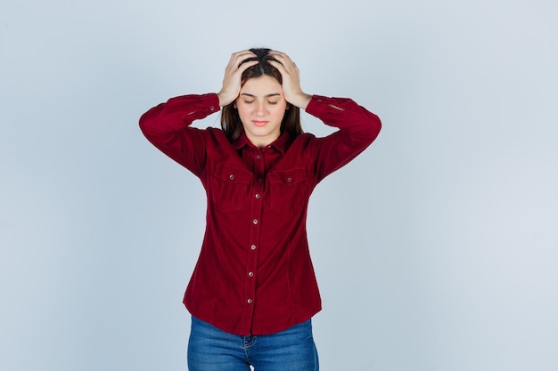 meisje in casual shirt houdt handen op het hoofd, sluit ogen en ziet er depressief uit