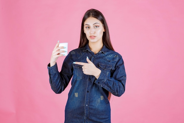 Meisje in denimoverhemd met een koffiekopje en voelt zich positief