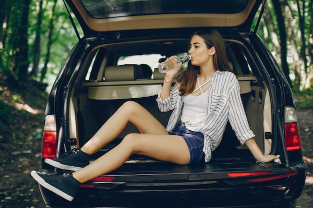 Meisje in een de zomerpark dichtbij auto