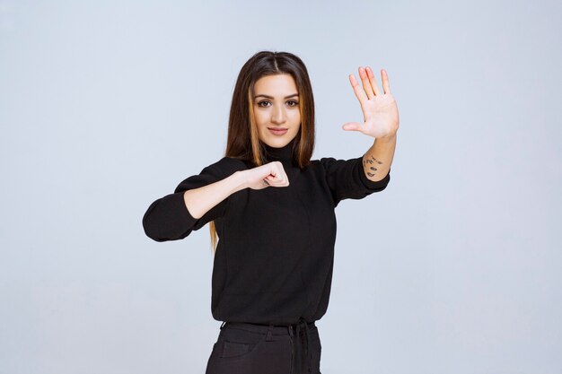 Meisje in een zwart shirt dat iets stopt en voorkomt. Hoge kwaliteit foto