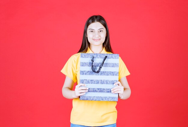 Meisje in geel shirt met een blauwe boodschappentas met patronen erop