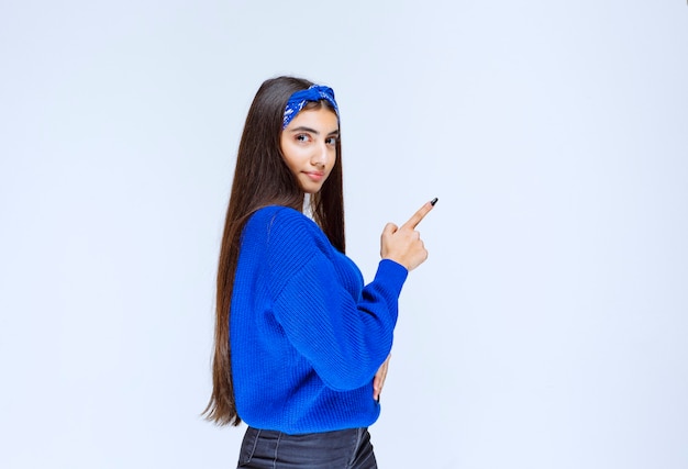 Meisje in het blauwe shirt wijzend naar iets aan de rechterkant.