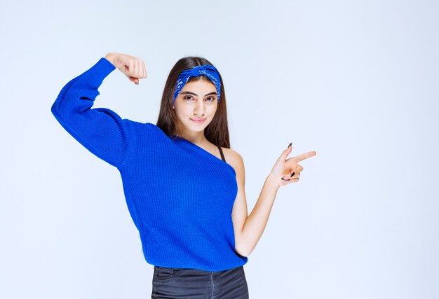 Meisje in het blauwe shirt wijzend naar iets aan de rechterkant.